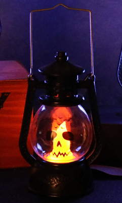 Lanterne tempête d’Halloween allumée, motif grimace